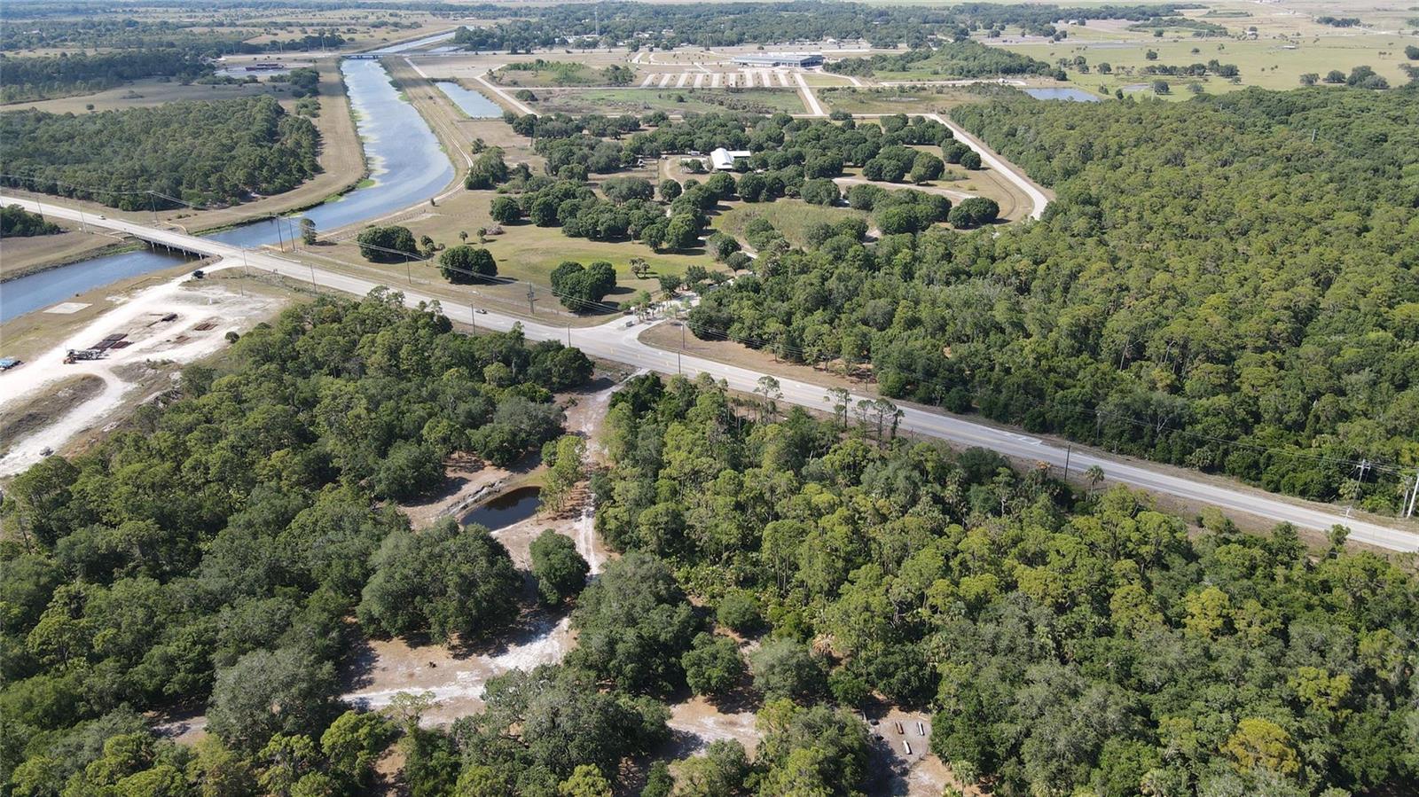 An aerial view shows a rural landscape with a road, a canal, and dense forest — 4340 Highway 710, Okeechobee FL 34974, OKEECHOBEE, FL