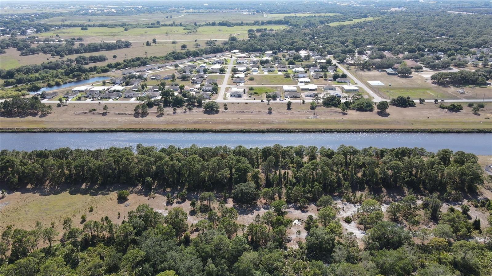 An aerial view shows a residential neighborhood separated from a wooded area by a canal — 4340 Highway 710, Okeechobee FL 34974, OKEECHOBEE, FL