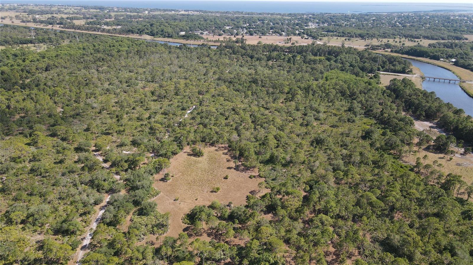 An aerial view shows a large, wooded lot with a central clearing and a nearby river — 4340 Highway 710, Okeechobee FL 34974, OKEECHOBEE, FL