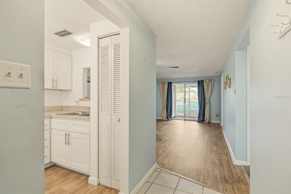 A view from a tiled entryway looking into a kitchen and a living area beyond — 3309 TROPHY BOULEVARD, NEW PORT RICHEY, FL