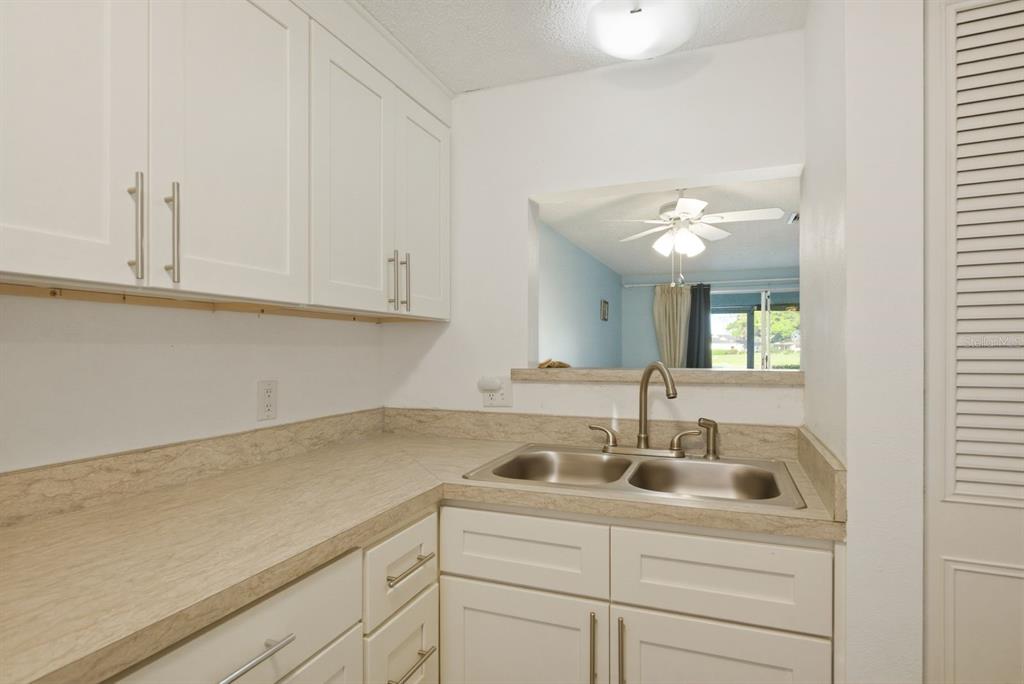 A kitchen features white cabinets, a light-colored laminate countertop, and a double-basin stainless steel sink — 3309 TROPHY BOULEVARD, NEW PORT RICHEY, FL