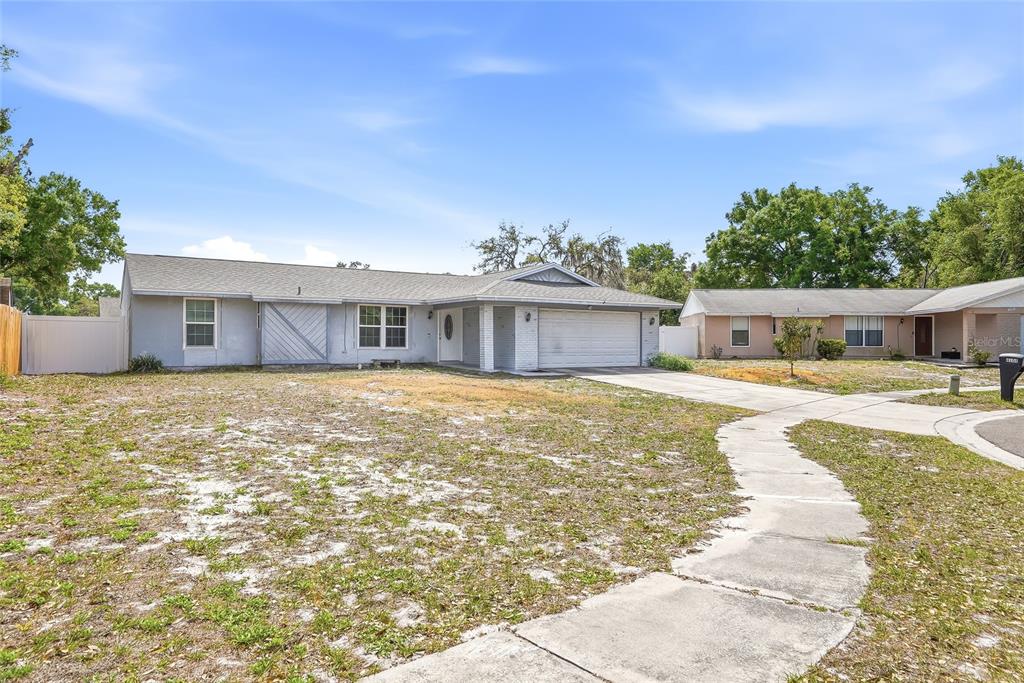 A single-story gray house with a two-car garage and a large, sparse front yard — 4104 FALLON COURT, BRANDON, FL