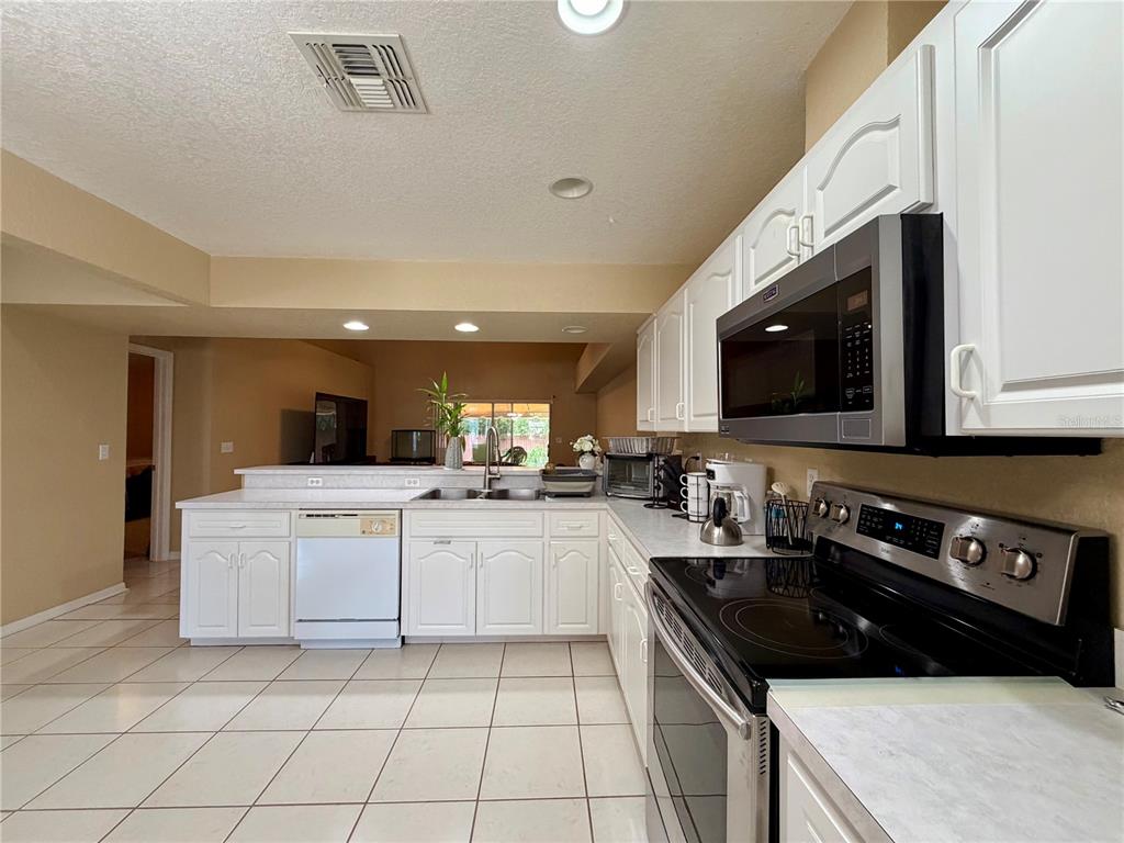 A kitchen with white cabinets, stainless steel appliances, and tile flooring — 1762 GREY FOX DRIVE, LAKELAND, FL
