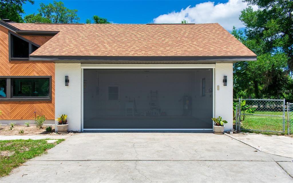 A house exterior featuring a garage with a dark mesh screen door and wood siding — 507 E HIGHWAY 318, CITRA, FL