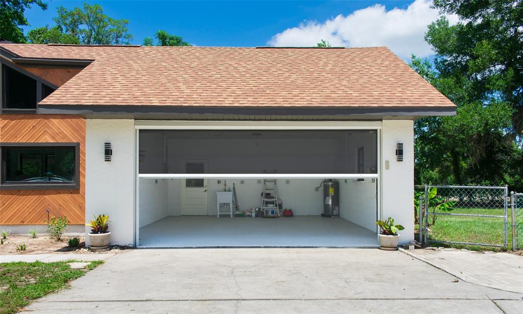 A garage with a retractable screen door, white walls, and a concrete floor — 507 E HIGHWAY 318, CITRA, FL