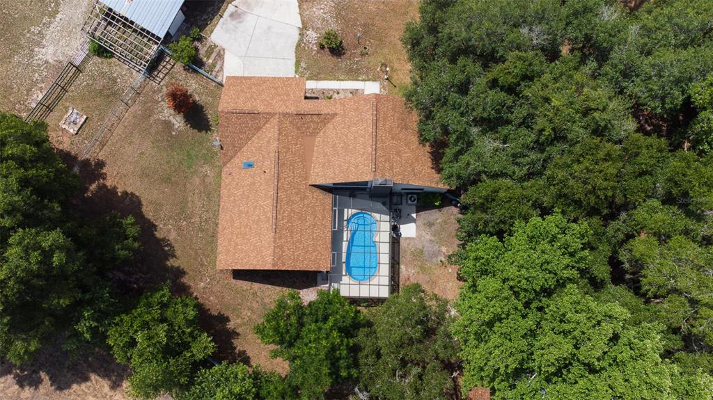 An aerial view shows a house with a brown shingled roof and a screened-in pool — 507 E HIGHWAY 318, CITRA, FL