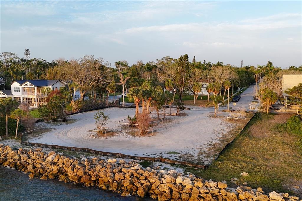An aerial view of a vacant, sandy waterfront lot bordered by a rock seawall — 603 INDIAN BEACH LANE, SARASOTA, FL