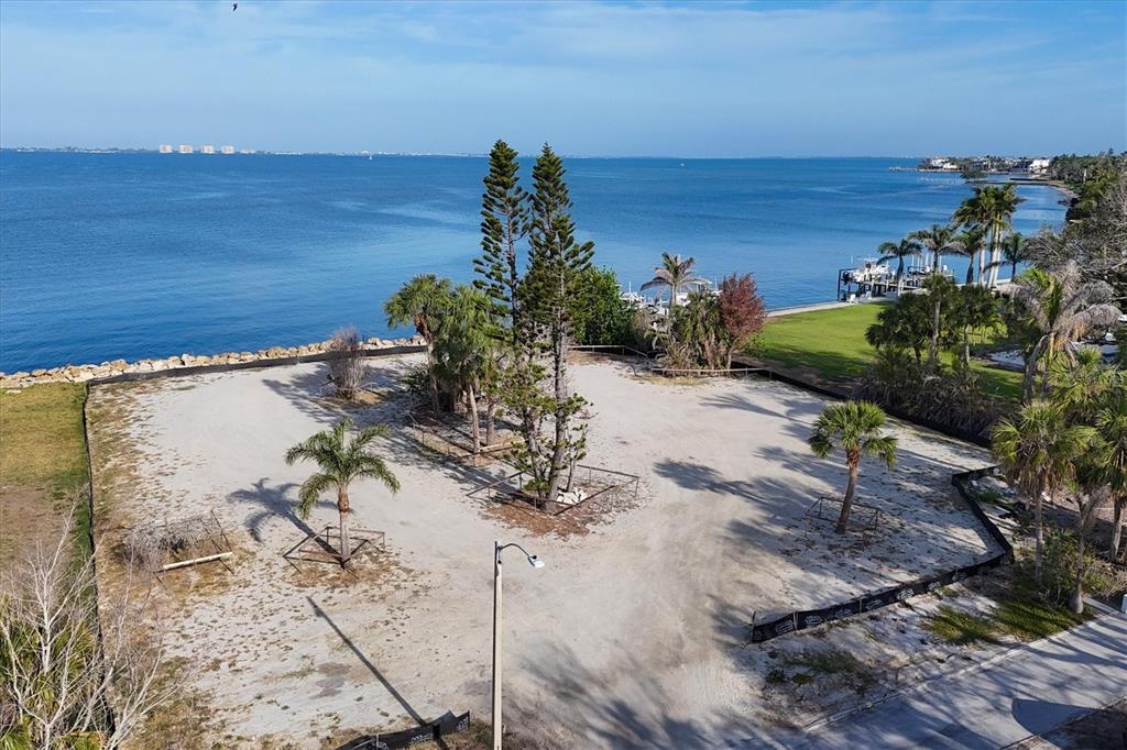 An aerial view of a vacant waterfront lot with several palm trees and sandy ground — 603 INDIAN BEACH LANE, SARASOTA, FL