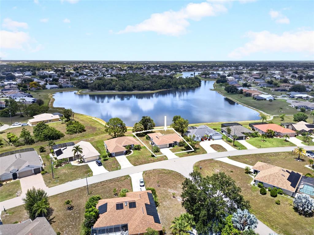 An aerial view shows a suburban house with a white outline near a lake — 25192 DERRINGER ROAD, PUNTA GORDA, FL