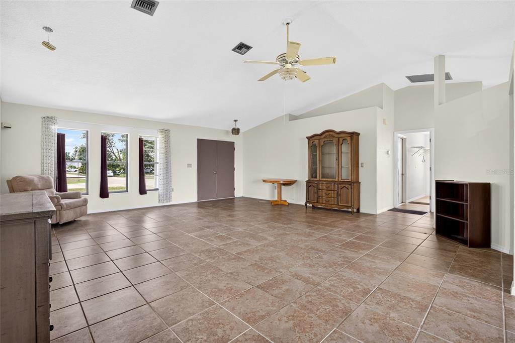 A spacious living room features light-colored walls, large tile flooring, and a vaulted ceiling — 25192 DERRINGER ROAD, PUNTA GORDA, FL