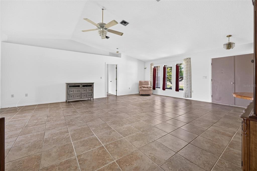 A spacious living room features white walls, vaulted ceilings, and large brown floor tiles — 25192 DERRINGER ROAD, PUNTA GORDA, FL