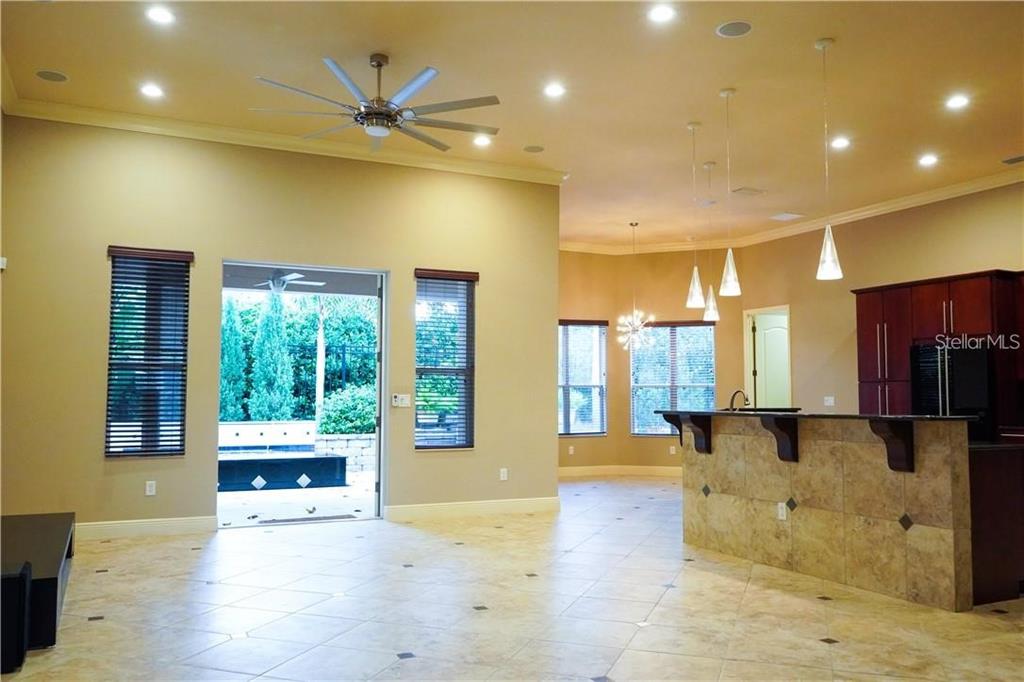 An open-concept living area features tile flooring, a kitchen island, and a sliding glass door — 10232 YONAOMI CIRCLE, CLERMONT, FL