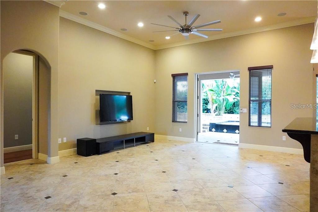 A living room features tile flooring, a recessed television, a ceiling fan, and patio access — 10232 YONAOMI CIRCLE, CLERMONT, FL