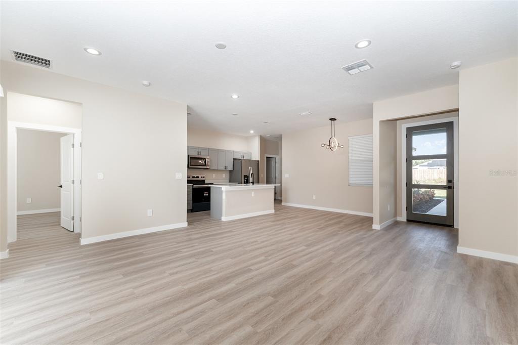 An open-concept kitchen and living area features light wood-look flooring and a glass-paneled door — 15615 SW 49TH AVENUE ROAD, OCALA, FL
