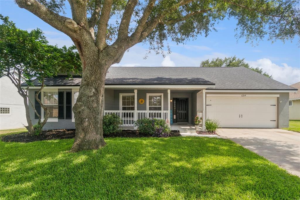 A single-story house with gray siding, a white garage door, and a large front tree — 1094 GOLF POINT LOOP, APOPKA, FL