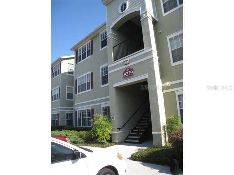 A three-story apartment building with a staircase leading to an entrance marked 8239 — 8103 LILLIES WAY UNIT 107, ORLANDO, FL