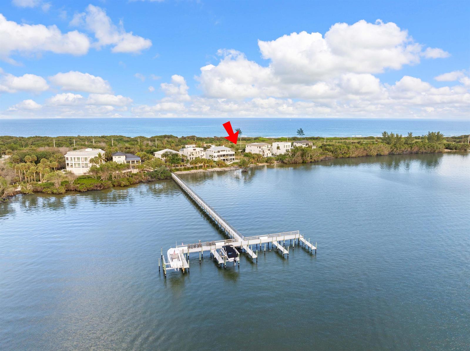 An aerial view shows waterfront houses with a long pier extending into the water — 7671 Pelican Pointe Drive, Jensen Beach FL 34957, JENSEN BEACH, FL