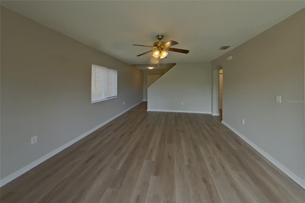 An empty living room features light gray walls, wood-look flooring, and a ceiling fan — 13130 FENNWAY RIDGE DRIVE, RIVERVIEW, FL