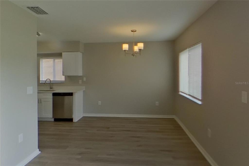 An open-concept dining area features light wood-look flooring, a chandelier, and an adjacent kitchen — 13130 FENNWAY RIDGE DRIVE, RIVERVIEW, FL