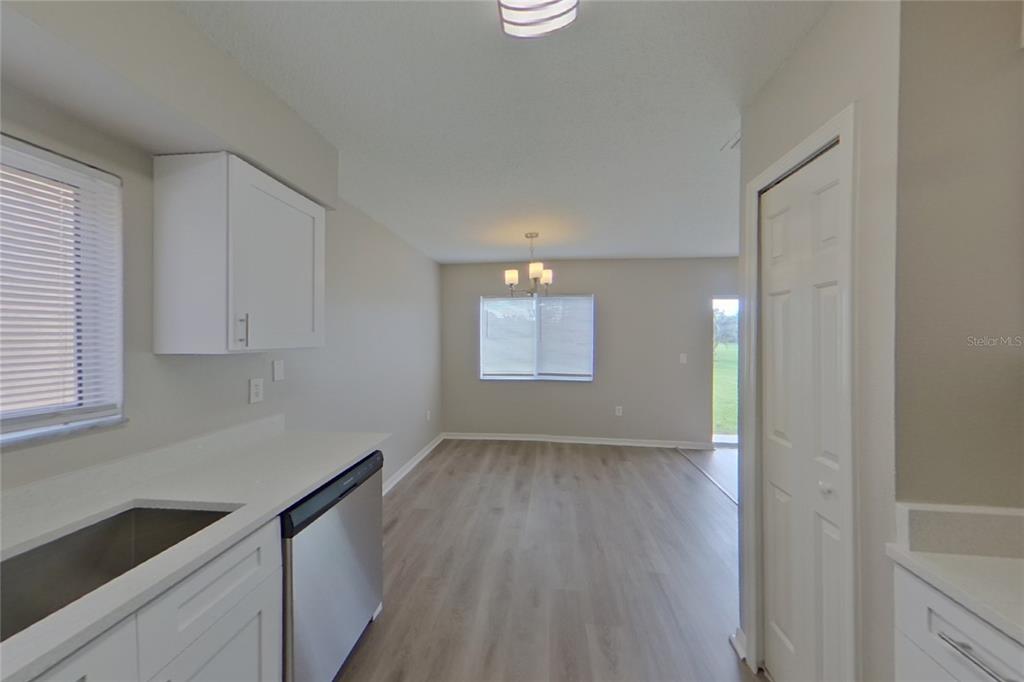 A kitchen with white cabinets and stainless steel appliances opens into a dining area — 13130 FENNWAY RIDGE DRIVE, RIVERVIEW, FL