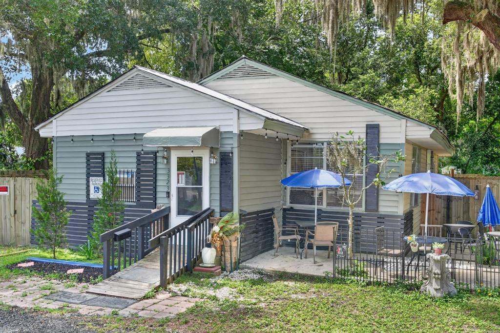 A single-story house with a wheelchair ramp, outdoor patio seating, and blue umbrellas — 3323 SAINT JOHNS AVENUE, PALATKA, FL