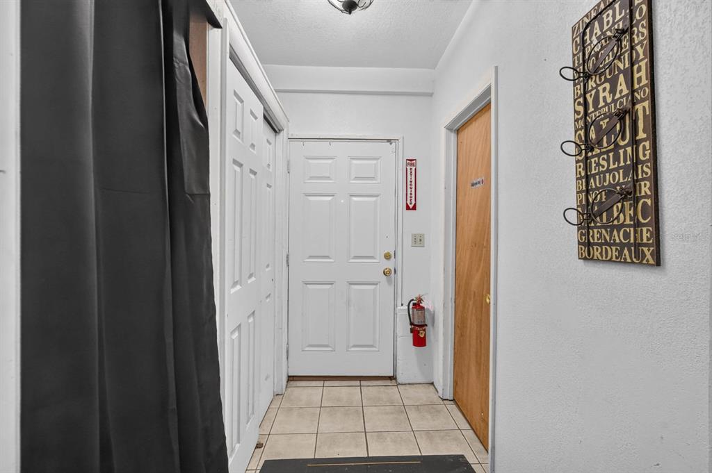 A tiled entryway features a white front door, a fire extinguisher, and wall-mounted wine decor — 3323 SAINT JOHNS AVENUE, PALATKA, FL