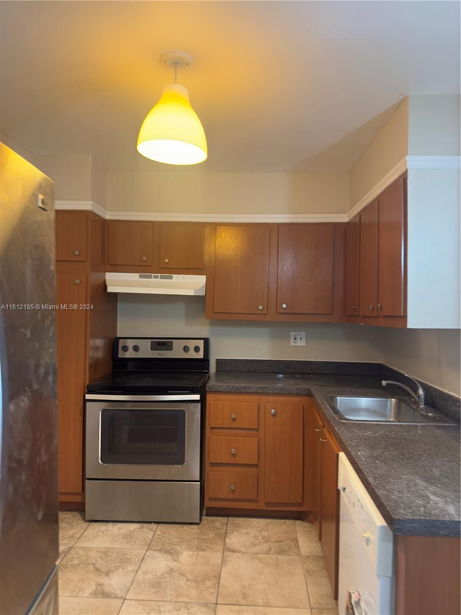 A kitchen with wood cabinets, stainless steel appliances, dark countertops, and tile flooring — 4324 NW 9th Ave # 3A, Deerfield Beach FL 33064, DEERFIELD BEACH, FL