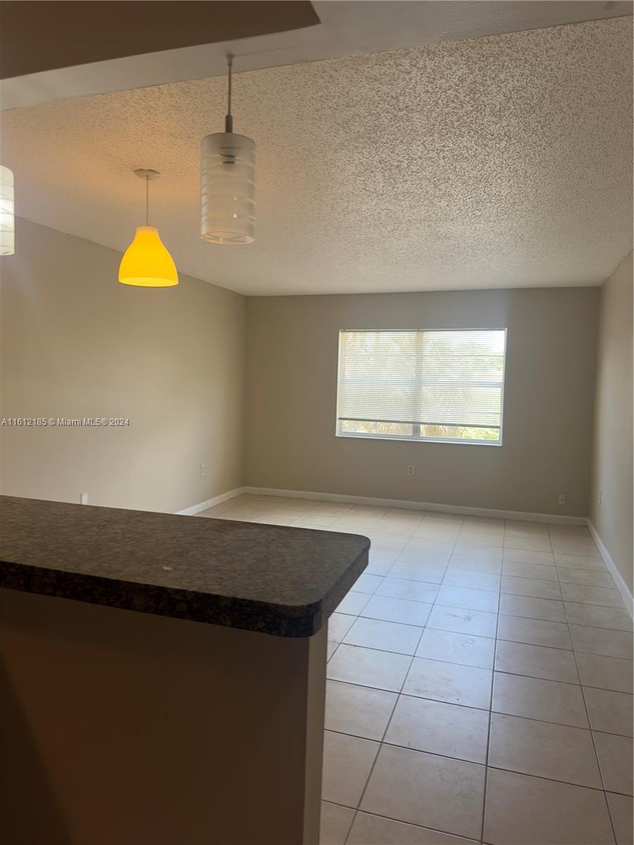 An empty room with beige walls, tile flooring, and two pendant lights over a counter — 4324 NW 9th Ave # 3A, Deerfield Beach FL 33064, DEERFIELD BEACH, FL