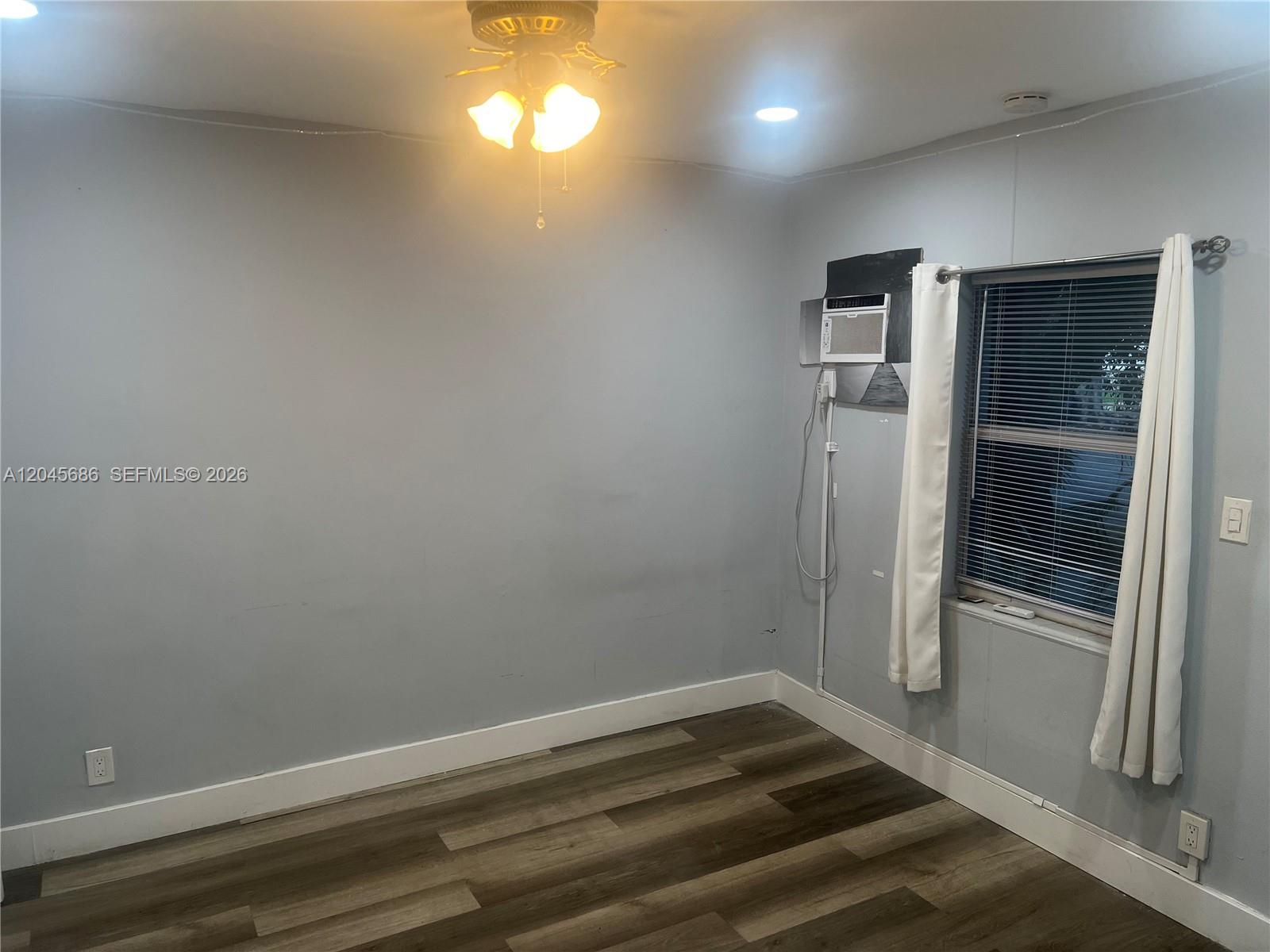 A room with light gray walls, wood-look flooring, a ceiling fan, and a window unit — 2118 N 19th Ave # 4, Hollywood FL 33020, HOLLYWOOD, FL