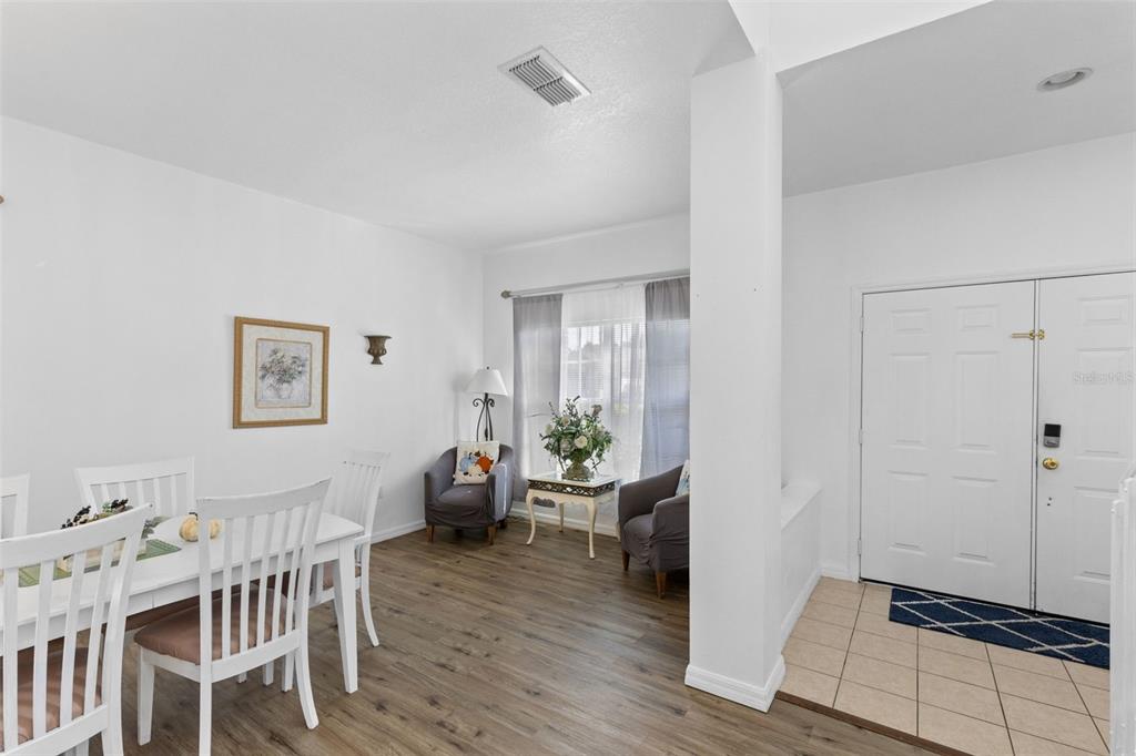 A dining area with wood-look flooring sits adjacent to a tiled entryway and front door — 4602 CUMBRIAN LAKES DRIVE, KISSIMMEE, FL