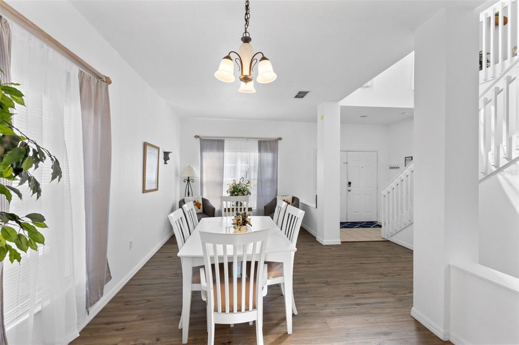 A dining room with white furniture, wood-look flooring, and a chandelier under a vaulted ceiling — 4602 CUMBRIAN LAKES DRIVE, KISSIMMEE, FL