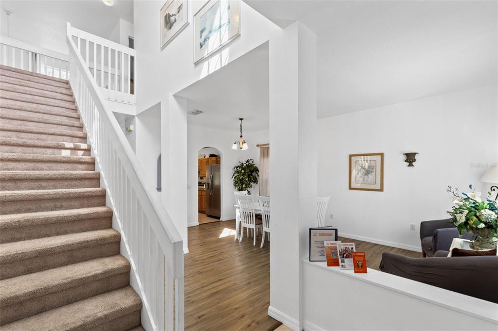 A carpeted staircase leads to a landing overlooking a dining area and living room — 4602 CUMBRIAN LAKES DRIVE, KISSIMMEE, FL