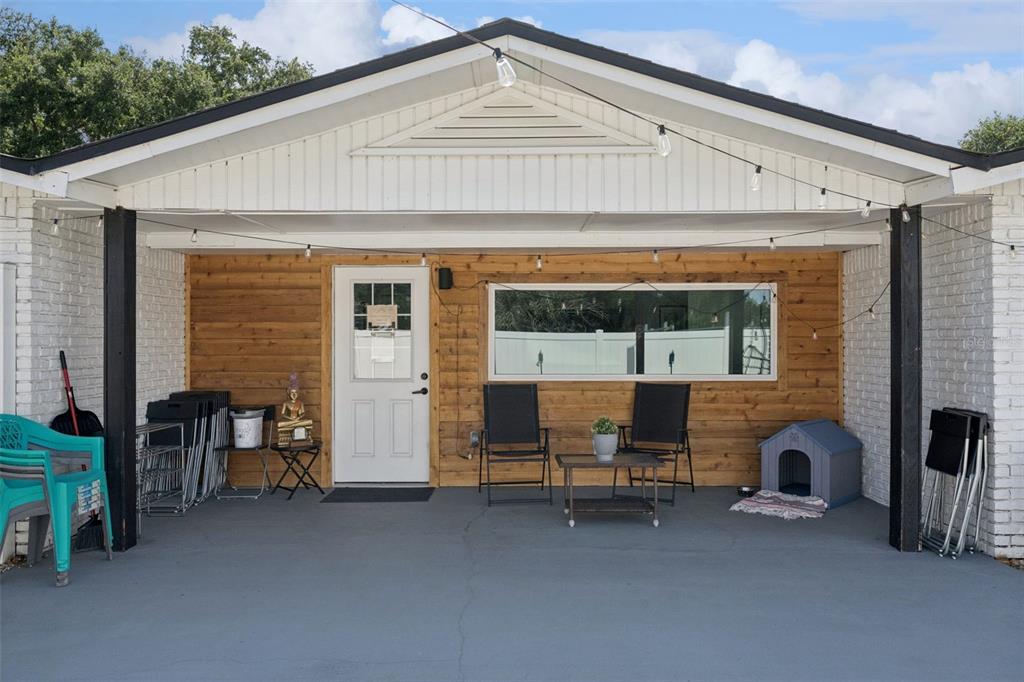 A covered patio features wood-paneled walls, a white door, a window, and outdoor seating — 273 AVALON ROAD, WINTER GARDEN, FL