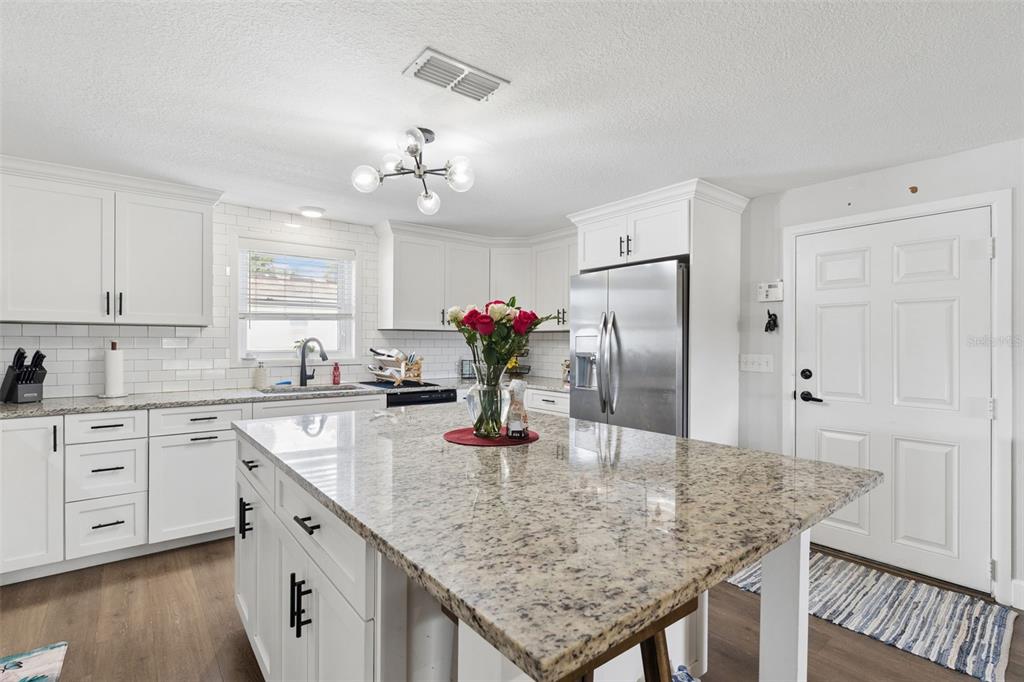 A kitchen features white cabinets, granite countertops, a central island, and stainless steel appliances — 273 AVALON ROAD, WINTER GARDEN, FL