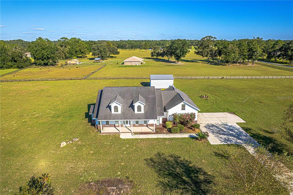 An aerial view shows a white house with a dark roof situated on a large lot — 879 NW MILO TERRACE, LAKE CITY, FL