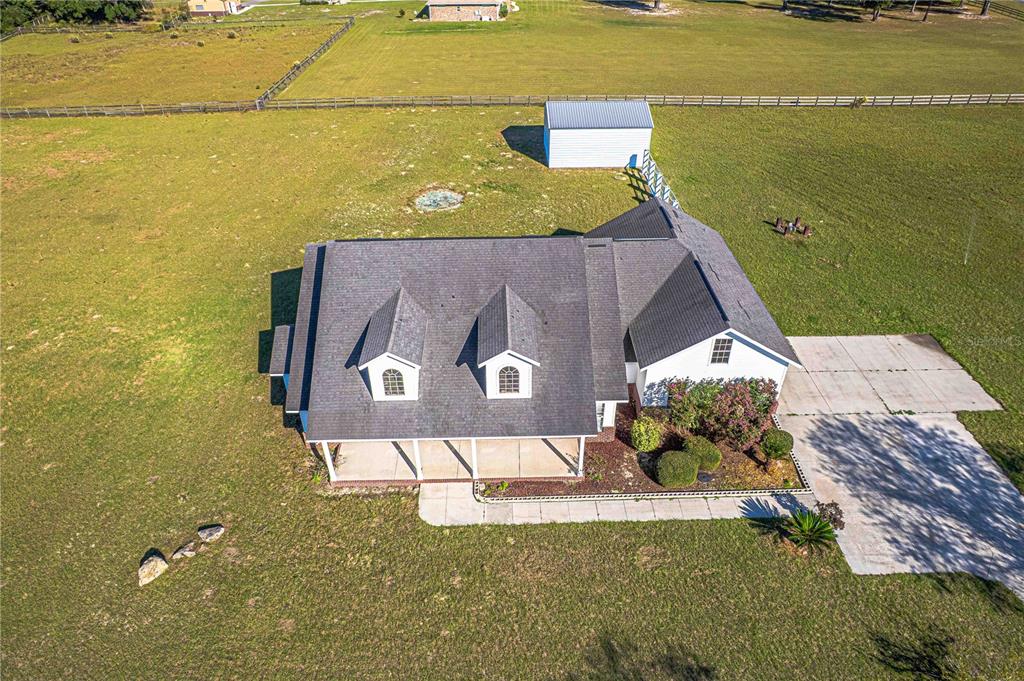 An aerial view shows a house with a dark roof, two dormers, and a detached shed — 879 NW MILO TERRACE, LAKE CITY, FL