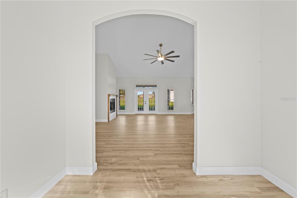 An arched doorway leads into a spacious living room with light wood-look flooring — 879 NW MILO TERRACE, LAKE CITY, FL
