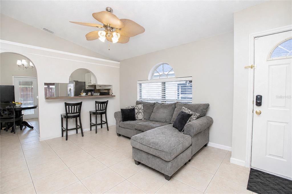 A living room features a gray sectional sofa, a breakfast bar with stools, and tile flooring — 519 BEASLEY COURT, ORLANDO, FL