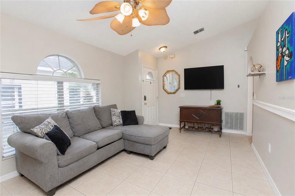 A living room features a gray sectional sofa, a wall-mounted television, and tile flooring — 519 BEASLEY COURT, ORLANDO, FL