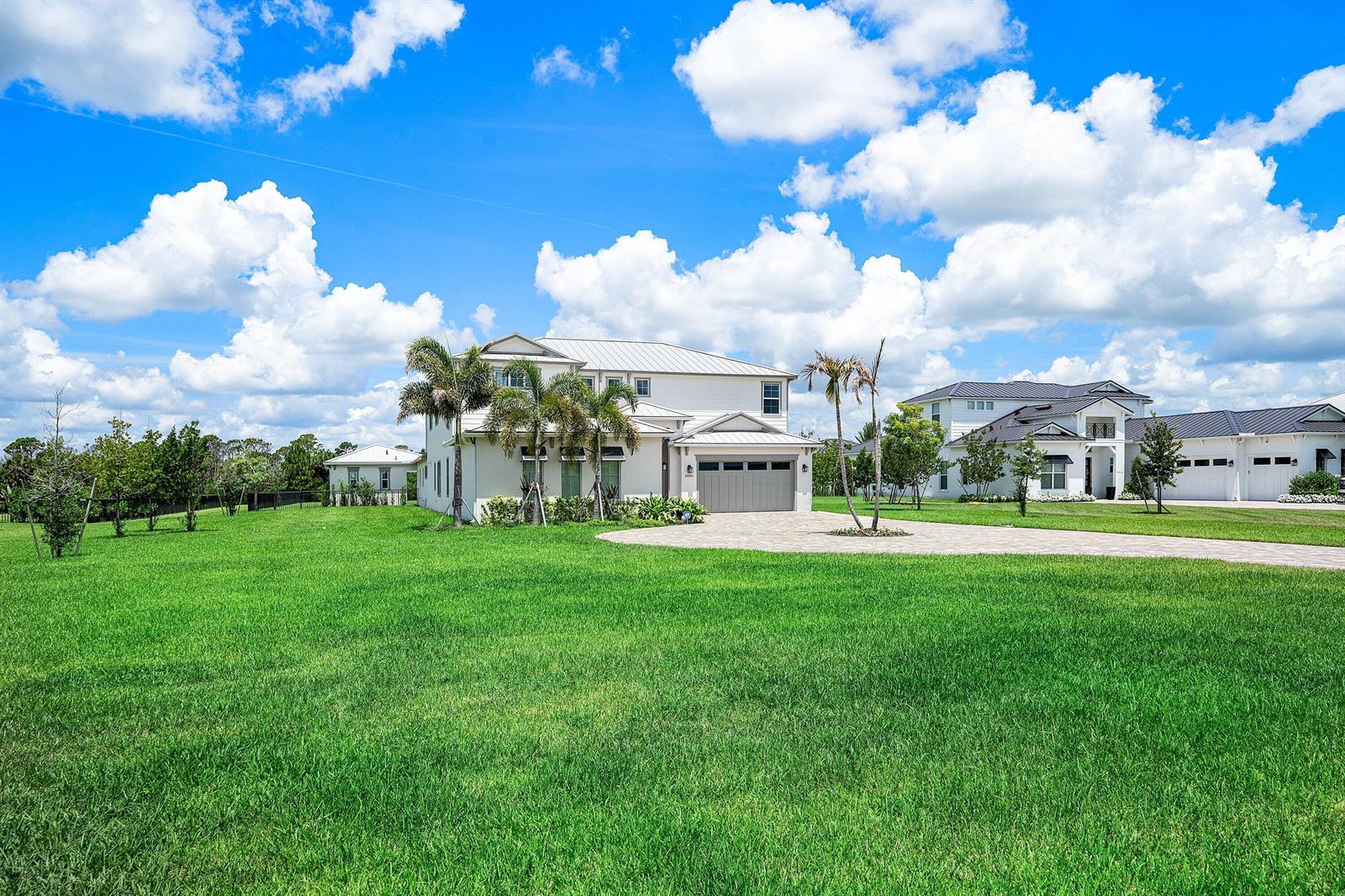 A large white two-story house with a paved driveway and palm trees on a lawn — 20020 SE Bridgewater Drive, Jupiter FL 33458, JUPITER, FL