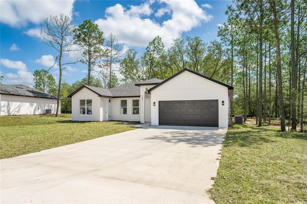 A white single-story house with a dark garage door and driveway sits on a grassy lot — 9609 N VAUGHN DRIVE, CITRUS SPRINGS, FL