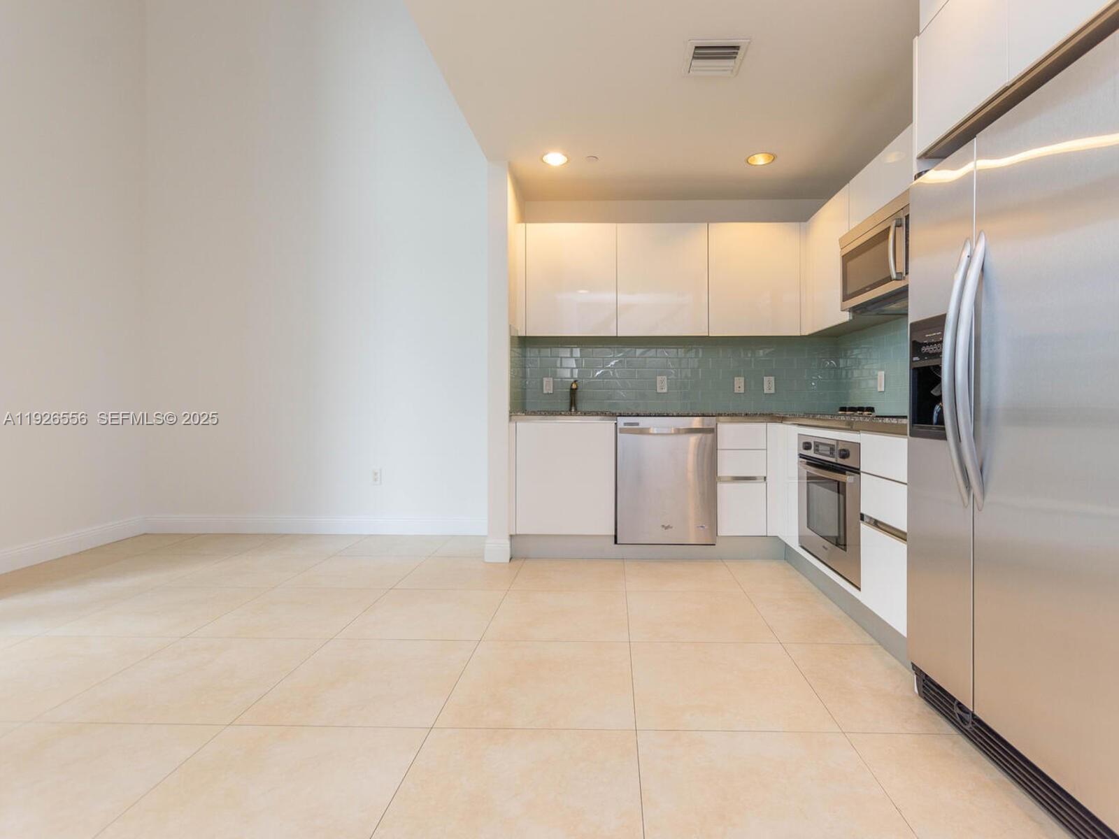 A modern kitchen features white cabinets, stainless steel appliances, and a light green backsplash — 1050 Brickell Ave # 606, Miami FL 33131, MIAMI, FL