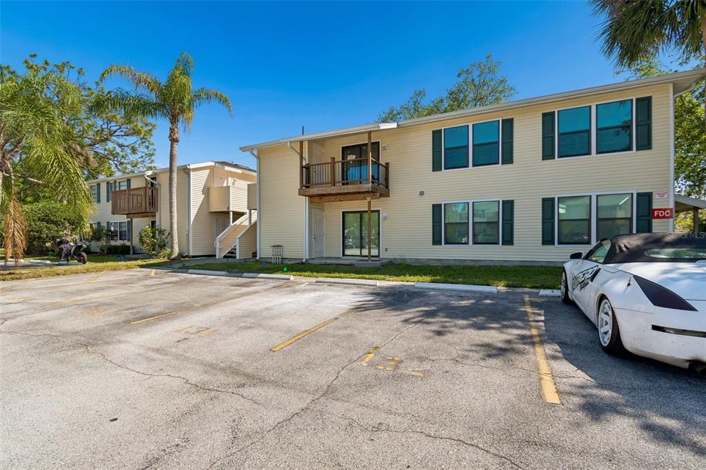 A two-story apartment building with yellow siding and a parking lot in the foreground — 140 HUNTER LAKE DRIVE UNIT 8C, OLDSMAR, FL