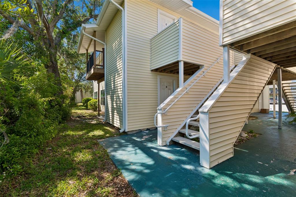 An exterior view of a two-story apartment building with beige siding and an outdoor staircase — 140 HUNTER LAKE DRIVE UNIT 8C, OLDSMAR, FL
