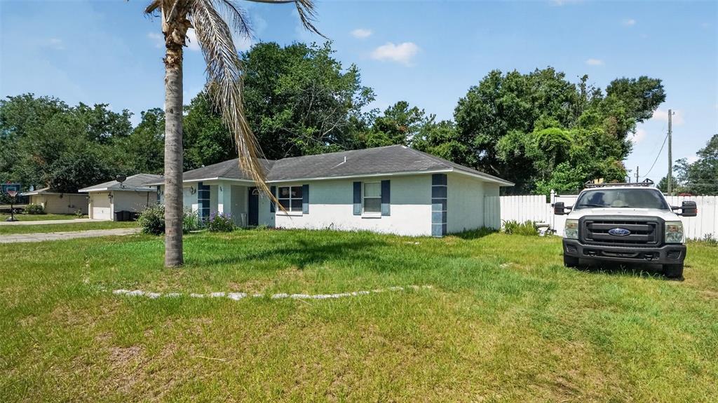 A single-story white house with a palm tree in the front yard and a truck — 24 PECAN COURSE LOOP, OCALA, FL