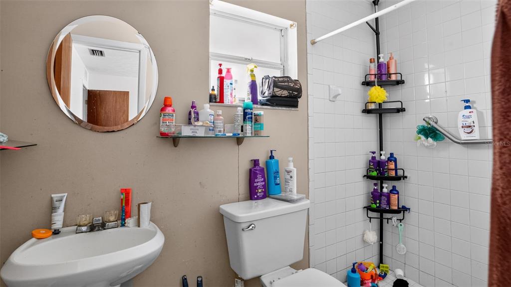 A bathroom features a pedestal sink, a toilet, a glass shelf, and a tiled shower — 24 PECAN COURSE LOOP, OCALA, FL