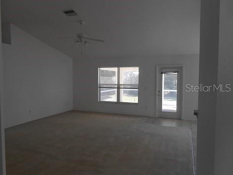 A carpeted living room features a vaulted ceiling, a ceiling fan, and a glass-paneled door — 1871 CALAHAN AVENUE, NORTH PORT, FL