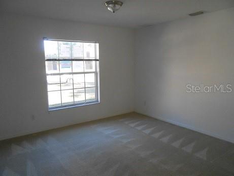 An empty bedroom with white walls, beige carpet, and a single window — 1871 CALAHAN AVENUE, NORTH PORT, FL