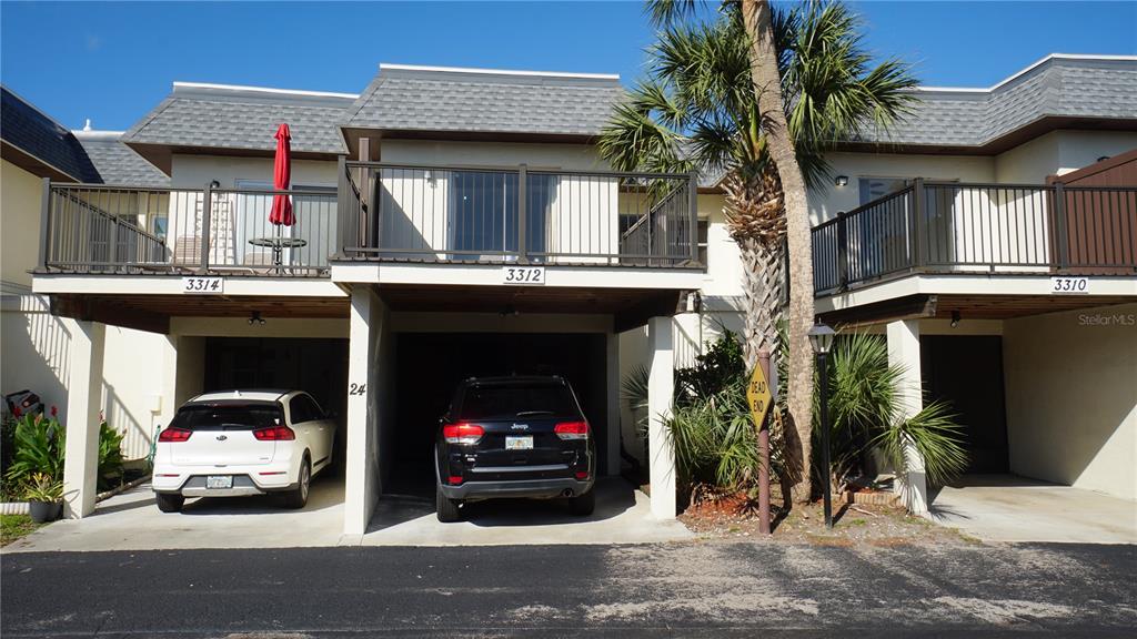 A multi-unit residential building features covered parking spaces, second-story balconies, and a palm tree — 3312 RAMBLEWOOD PLACE, SARASOTA, FL