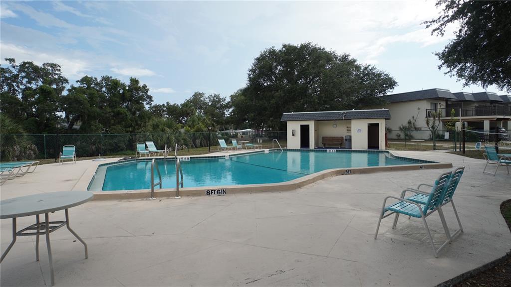 An outdoor swimming pool with a depth marker and a small covered building nearby — 3312 RAMBLEWOOD PLACE, SARASOTA, FL